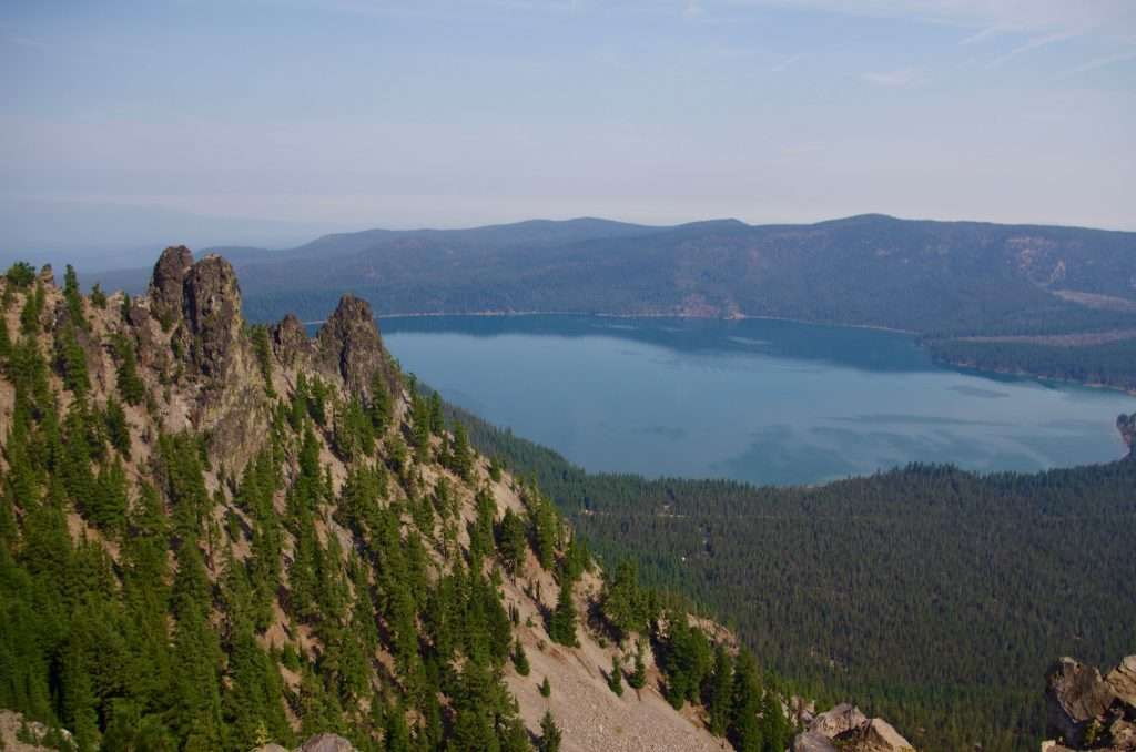 Rock formations on a steep slope, with a lake below.