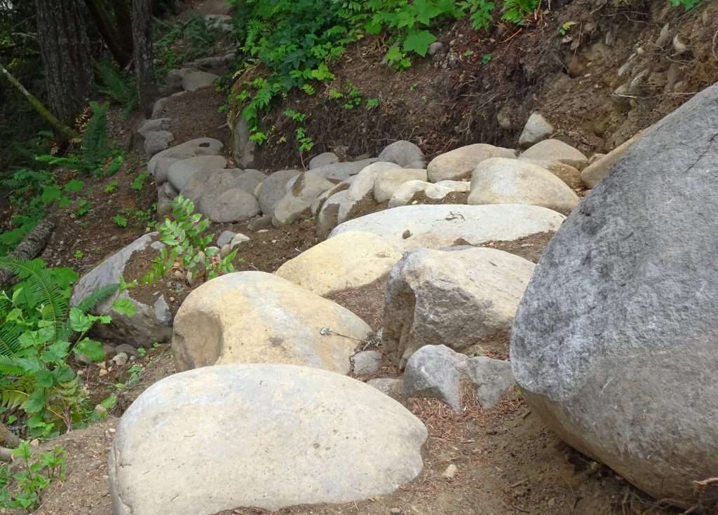 Alt Text: Dozens of boulders arranged in a curve descending a steep slope.