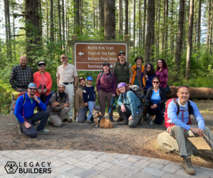 A large group gathers around a trail sign at Silver Falls State Park.