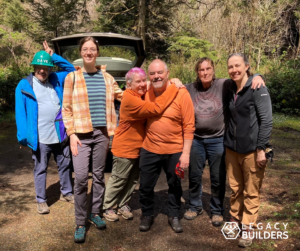 A group of volunteers pose together after a trail day, two of them hugging one another.