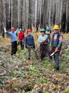 A group of volunteers celebrate in an open forest.